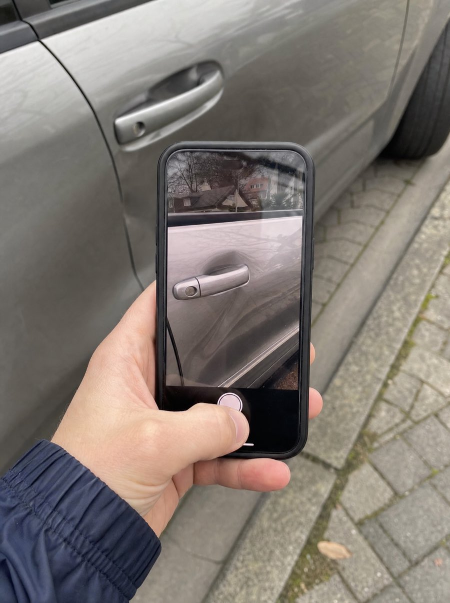 Eine Hand fotografiert mit dem Smartphone einen Schaden an einer Autotür